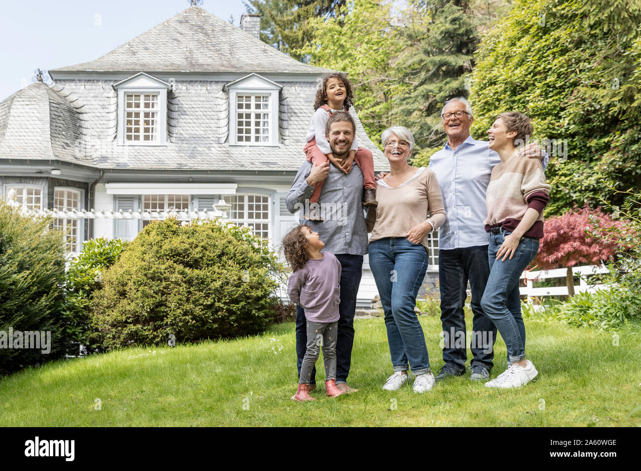 Happy extended family standing in garden of their home Stock Photo