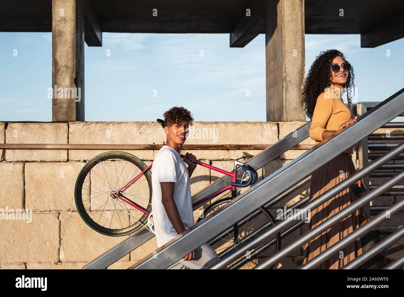 Young couple climbing stairs, carrying bicycle Stock Photo