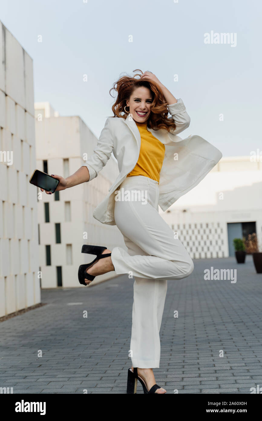 Happy businesswoman in white pant suit, jumping and dancing in the