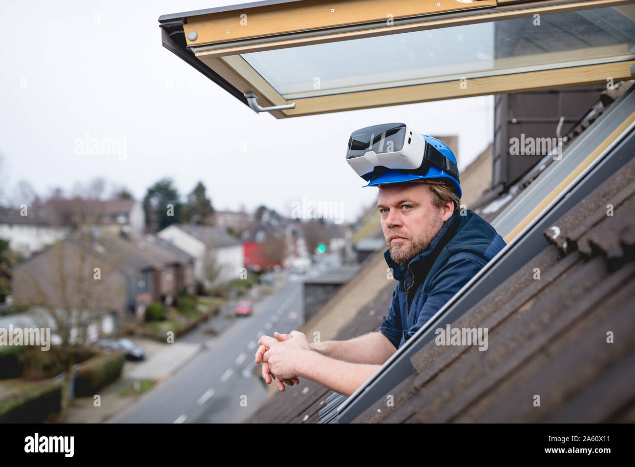 Architect with VR goggles on his safety helmet, looking out of rooflight Stock Photo