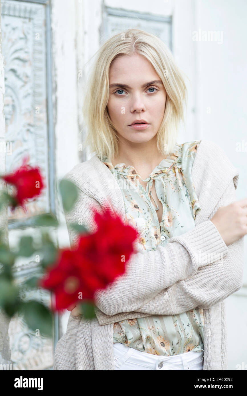 Portrait of blond young woman wearing summer blouse with floral design and cardigan Stock Photo