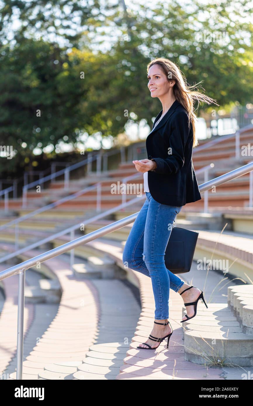 Businesswoman with a handbag walking down stairs Stock Photo