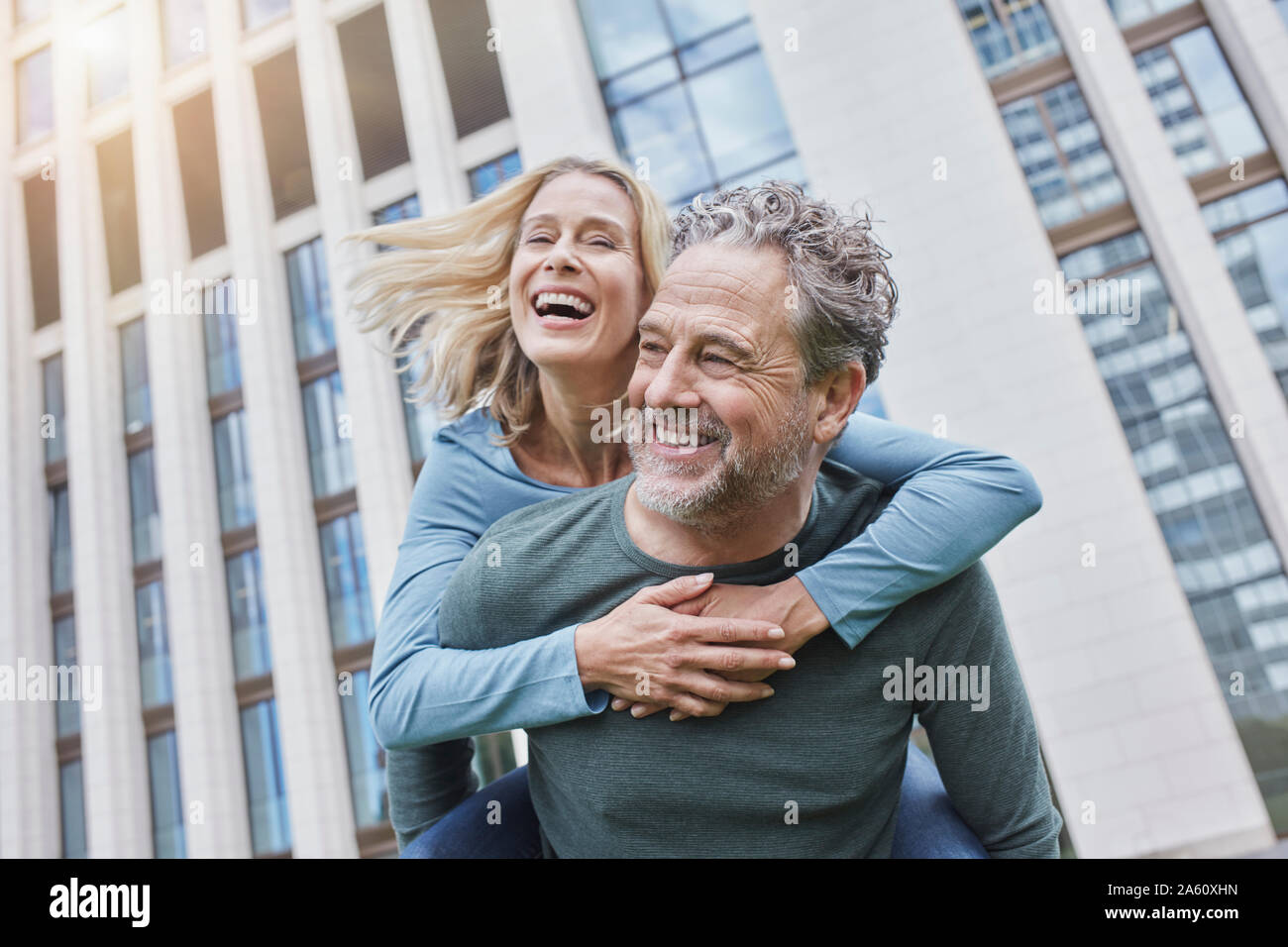 Happy mature man carrying woman piggyback in the city Stock Photo