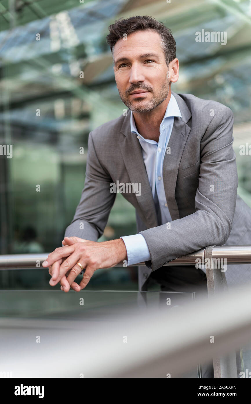 Businessman in the city leaning on railing Stock Photo