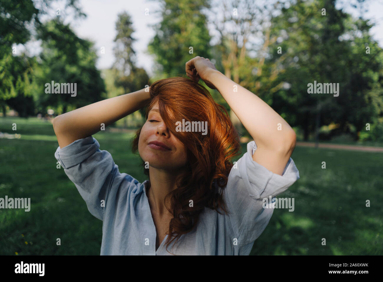 Portrait of redheaded woman in a park Stock Photo - Alamy