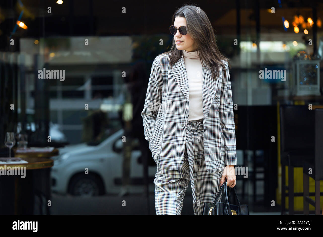 Stylish woman standing outside a restaurant looking around Stock Photo