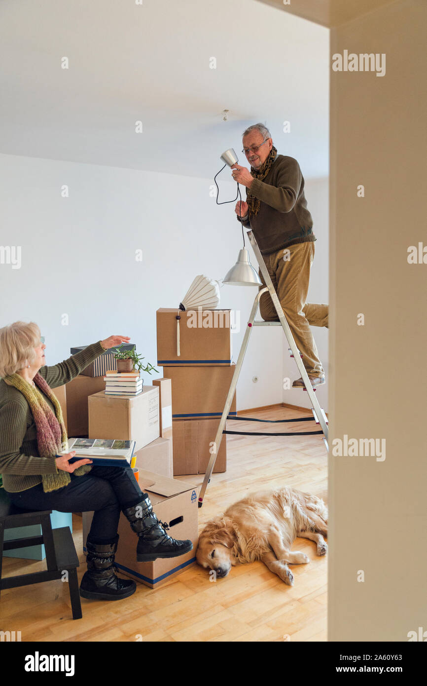 Senior couple in a new home with man mounting ceiling lamp Stock Photo ...