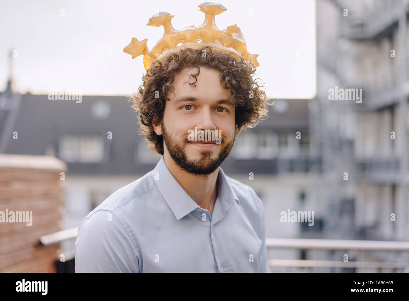 Portrait of confident businessman on roof terrace wearing a crown Stock Photo
