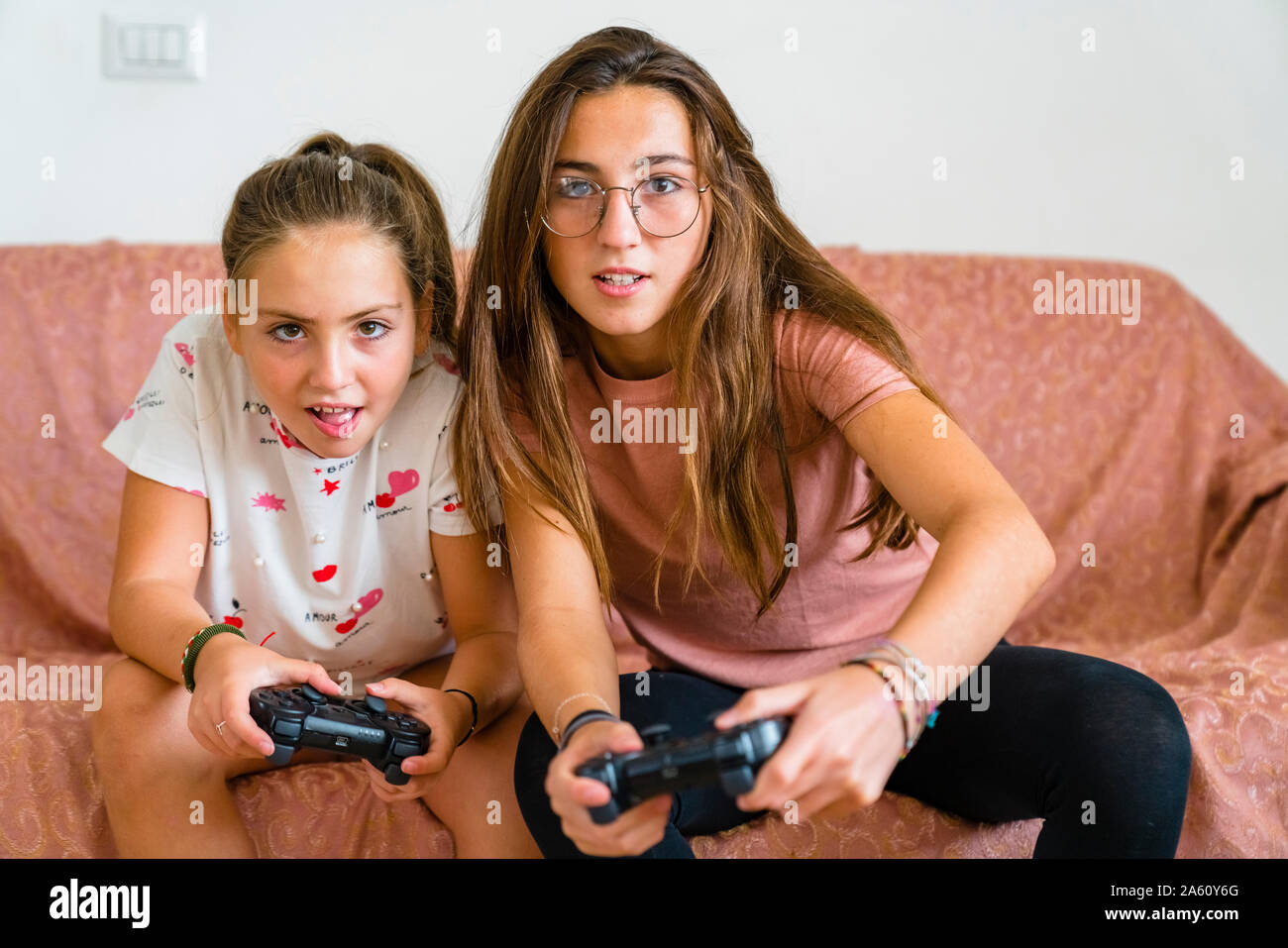 Sisters playing video game on couch at home Stock Photo