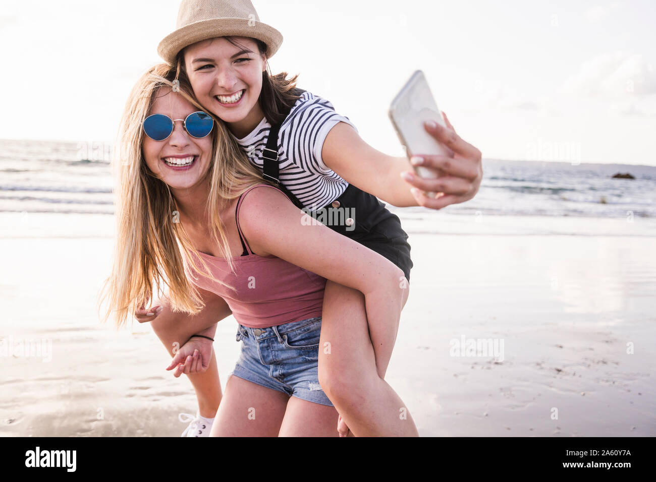 Two Girlfriends Having Fun On The Beach Carrying Each Other Piggyback two-girlfriends-having-fun-on-the-beach-carrying-each-other-piggyback