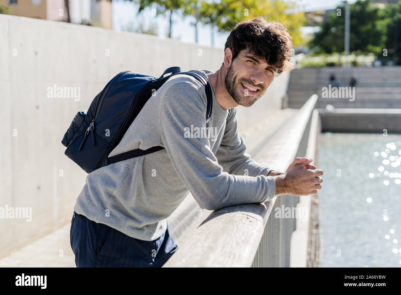 Portrait of smiling man with backpack having a break in the city Stock Photo
