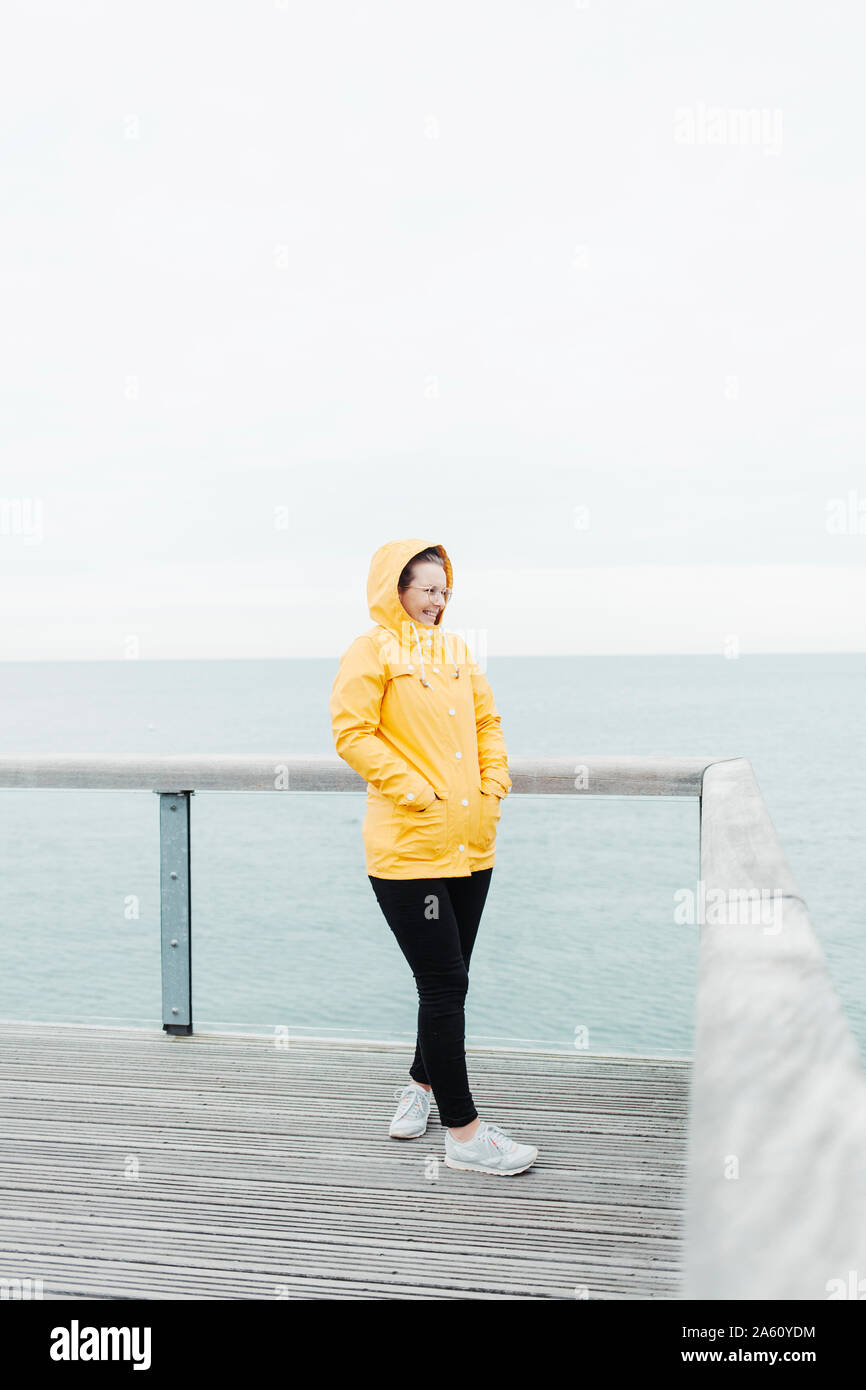 Young woman wearing yellow rain coat Stock Photo - Alamy