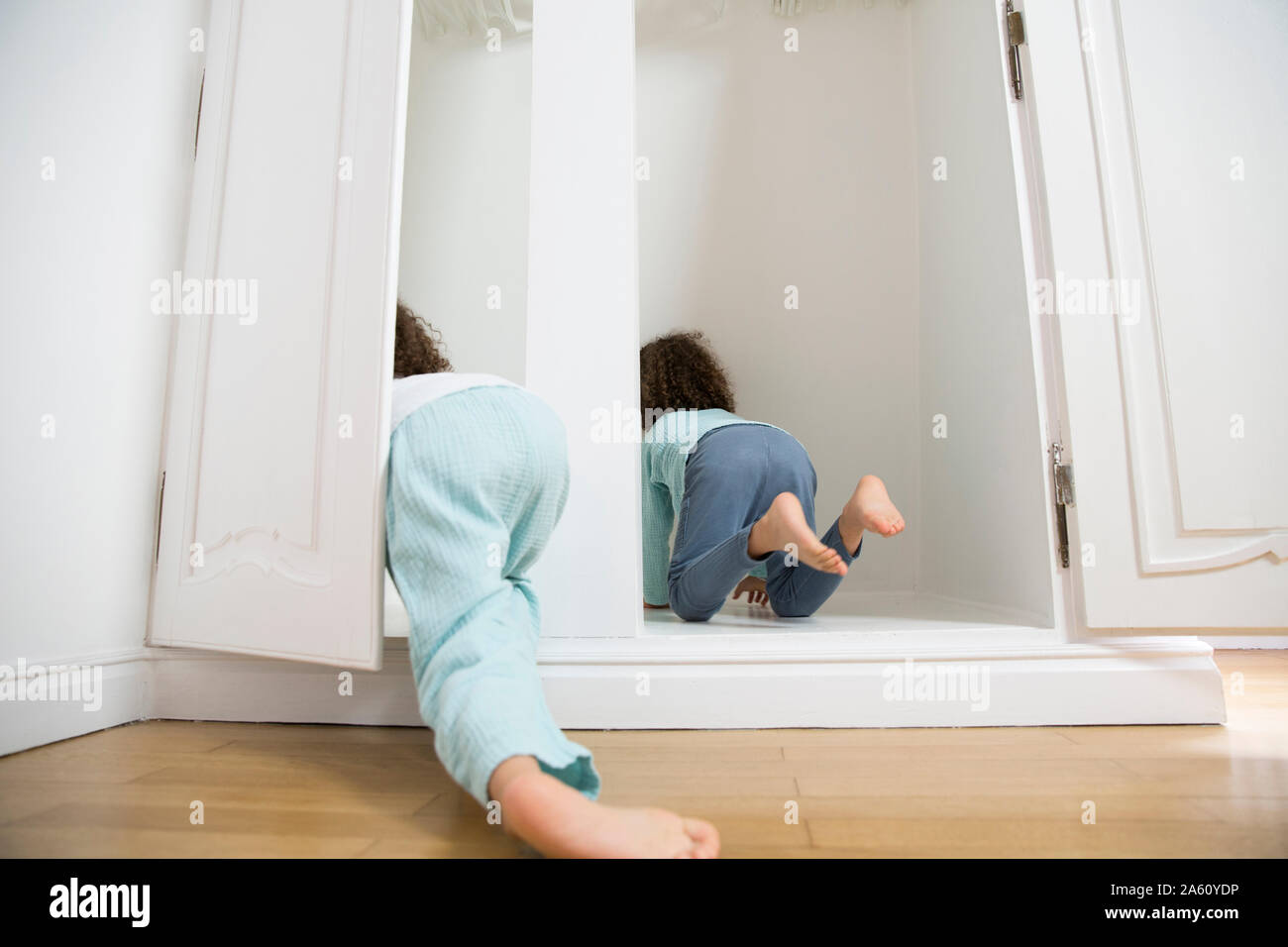 Two twin brothers crawling into wardrobe at home Stock Photo
