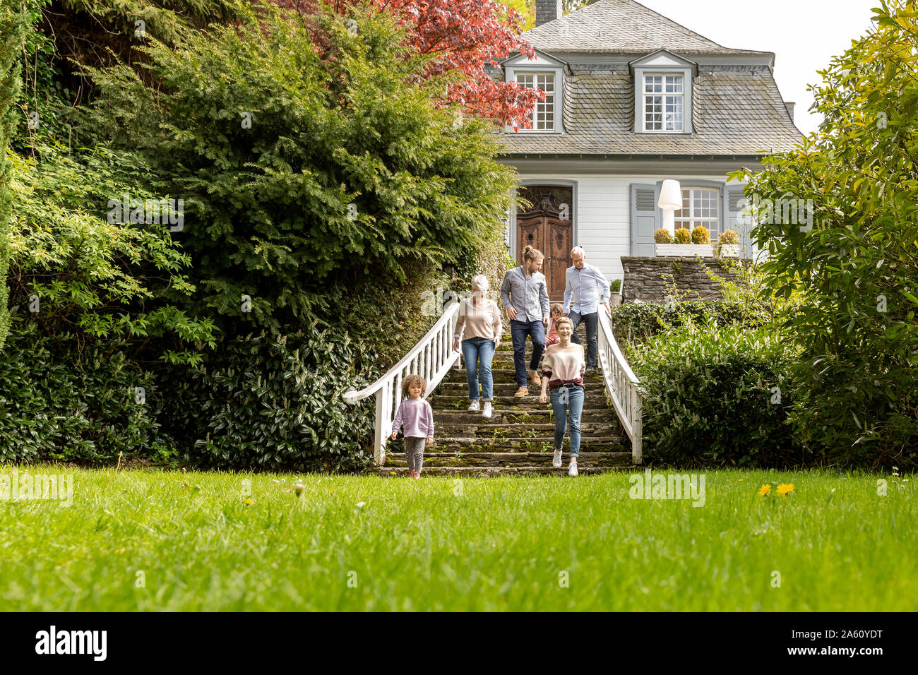 Extended family walking on stairs in garden of their home Stock Photo