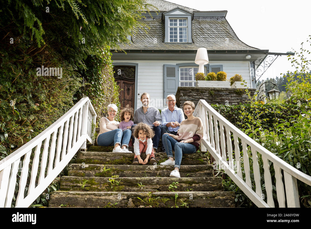 Happy extended family sitting on stairs in garden of their home Stock Photo