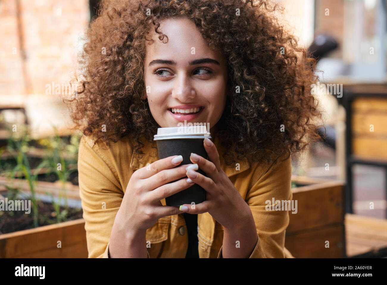 Portrait of smiling teenage girl drinking coffee to go outdoors Stock Photo