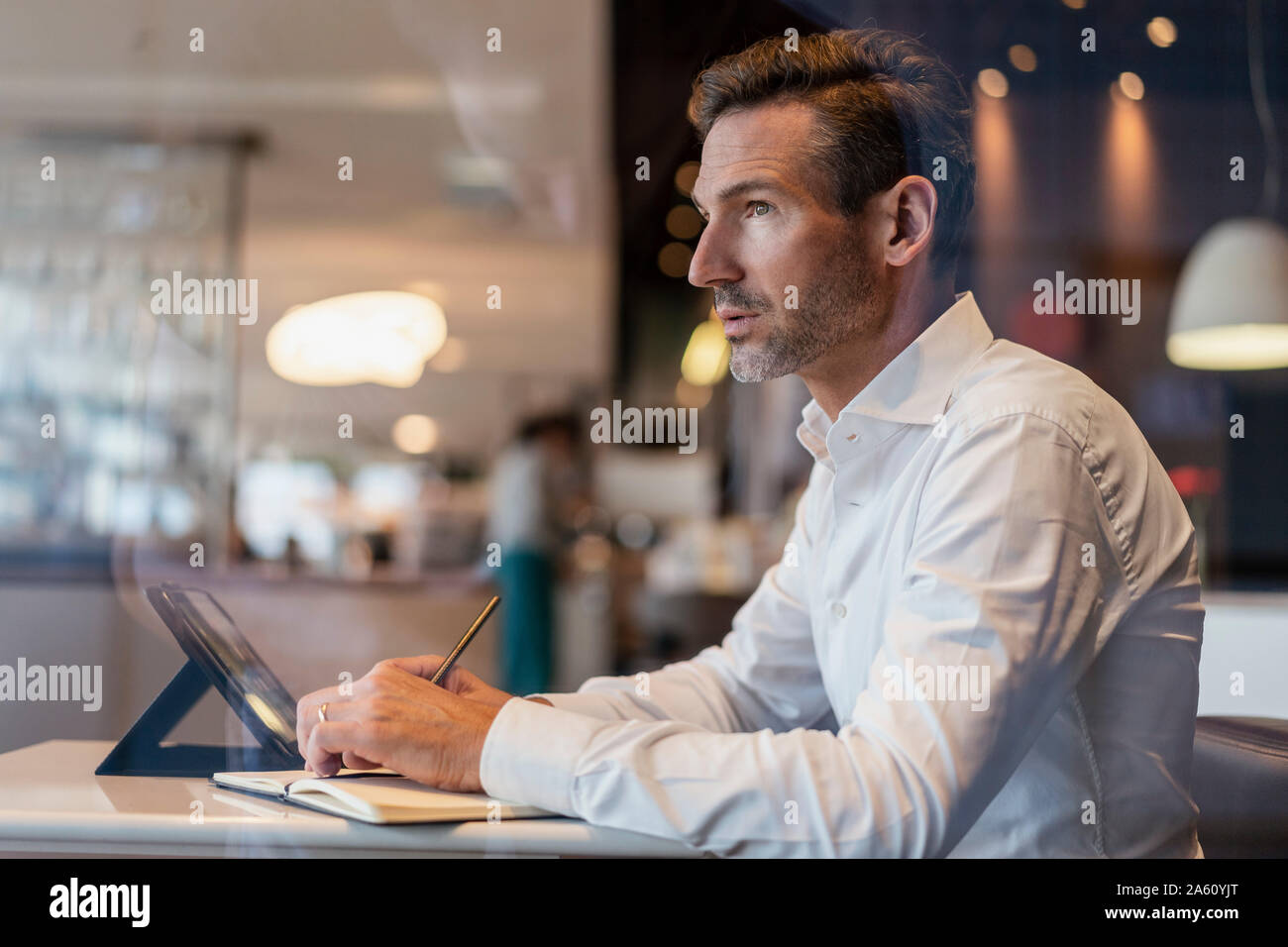 Businessman with tablet in a cafe taking notes Stock Photo