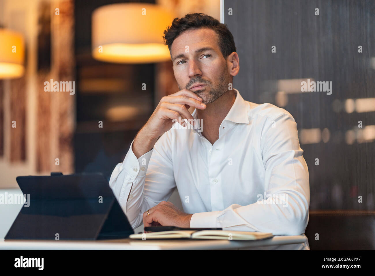 Businessman with tablet and notebook in a cafe thinking Stock Photo