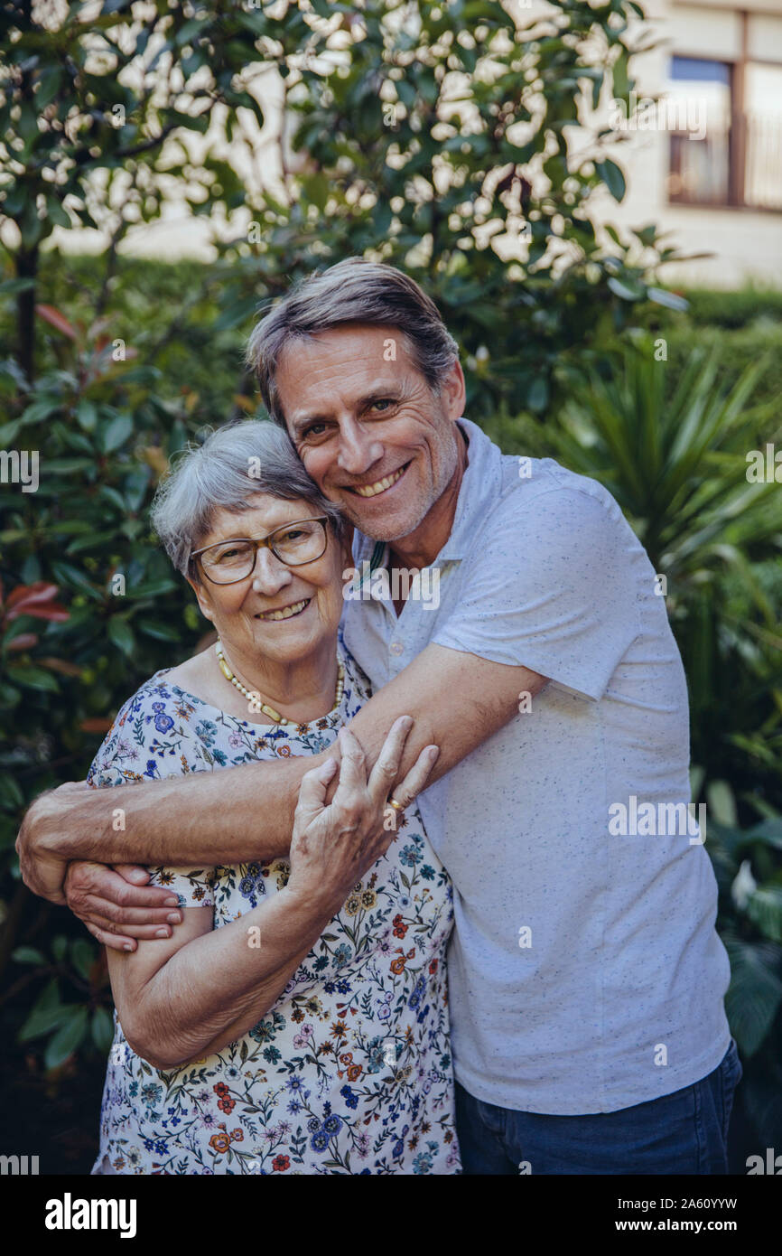 Adult son embracing his mother in the garden Stock Photo