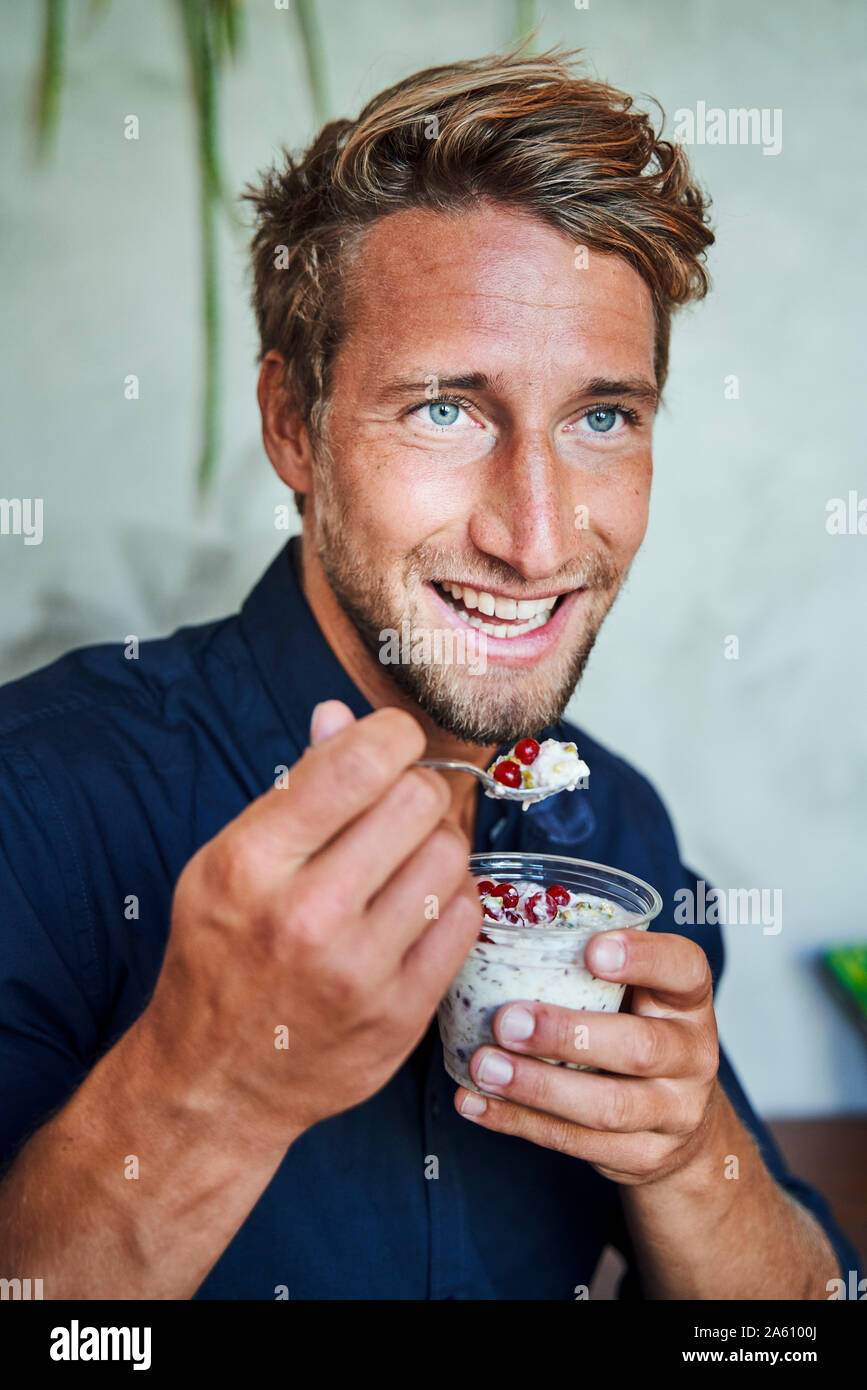 Portrait of smiling young man eating muesli Stock Photo