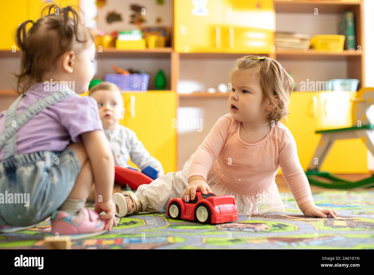 Nursery babies girls and boy playing together in a play room in