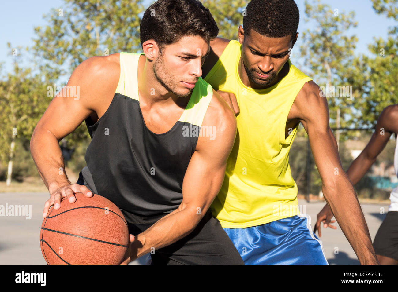 Young men playing basketball and dribbling ball on sports ground Stock Photo