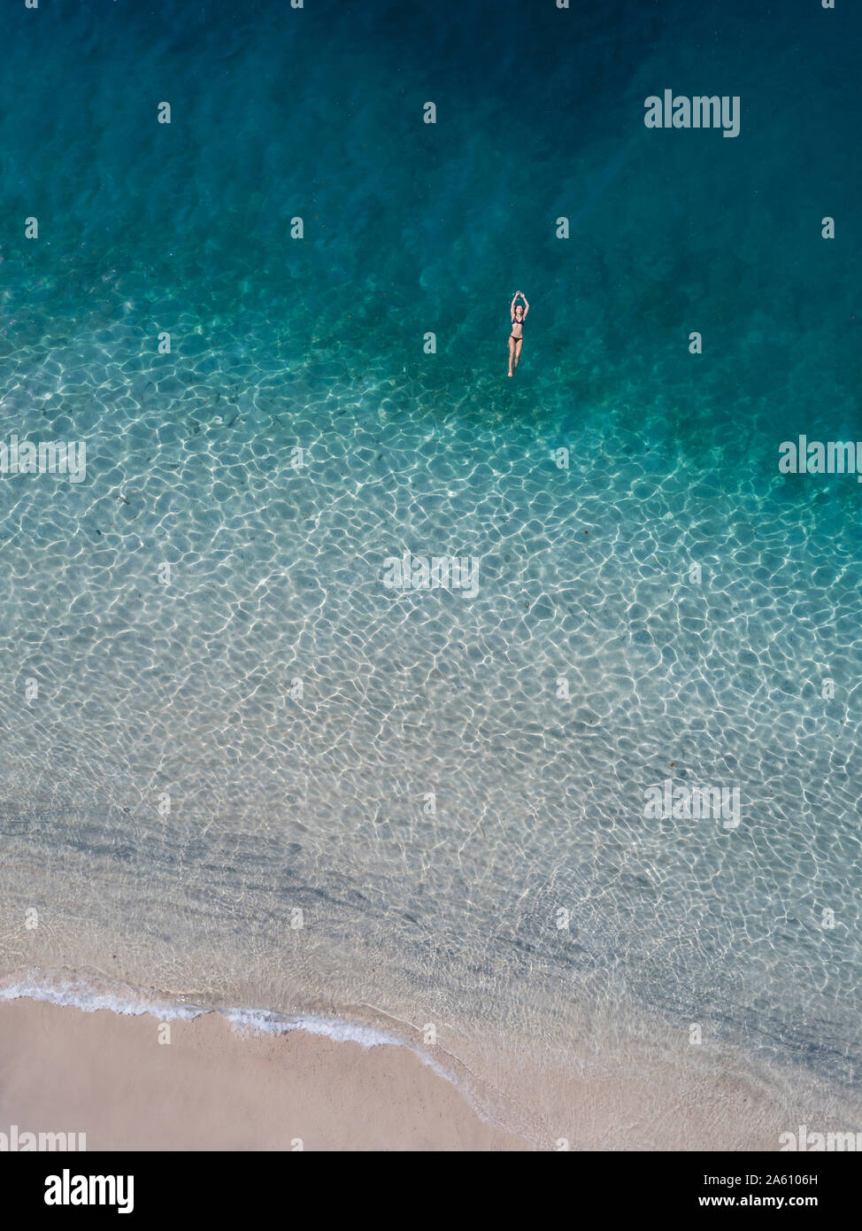 side view of young woman in swimming suit surfing alone in ocean