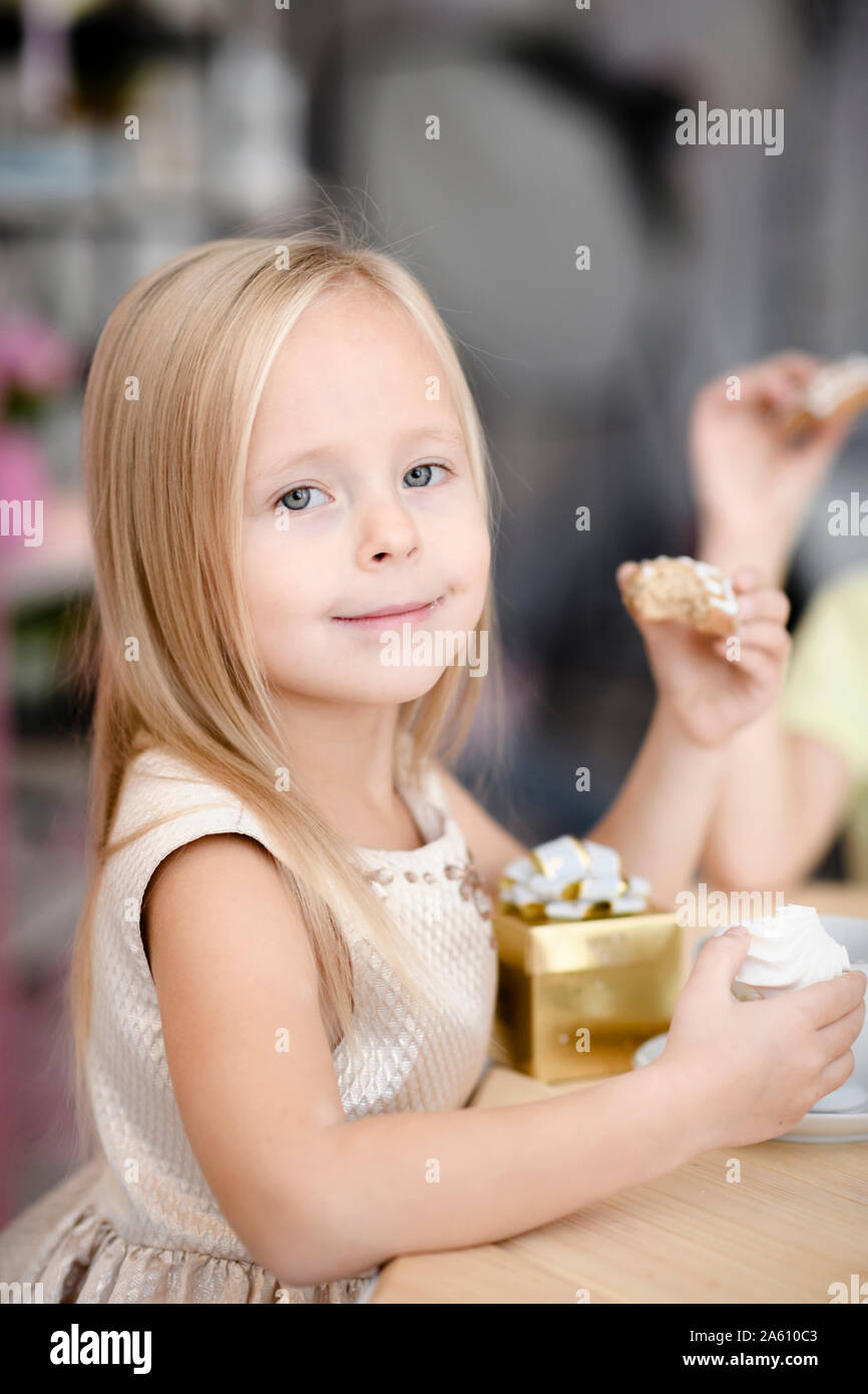 Portrait of smiling little girl with gift box eating cookies Stock Photo