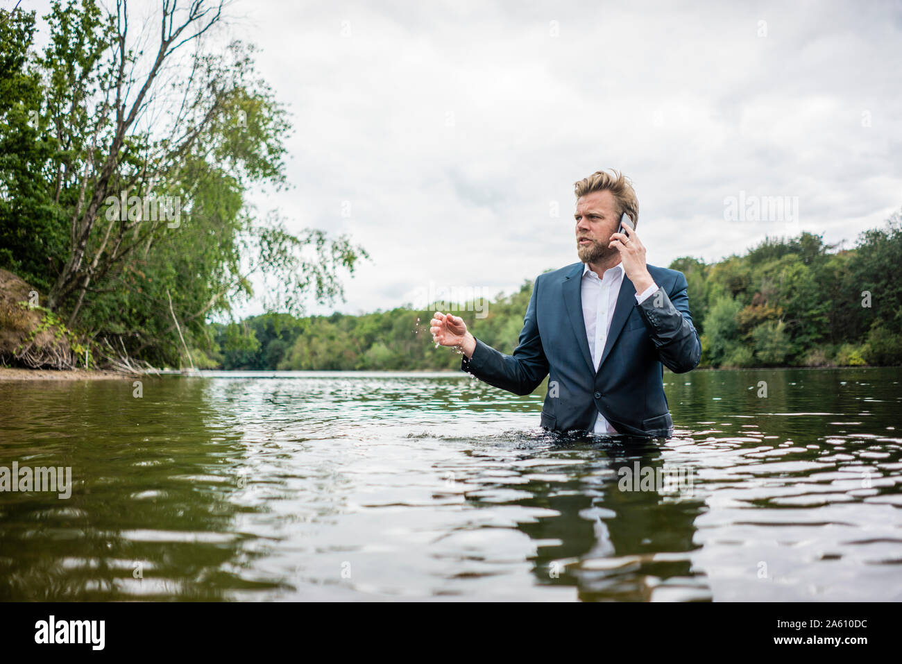 Businessman standing in a lake talking on the phone Stock Photo