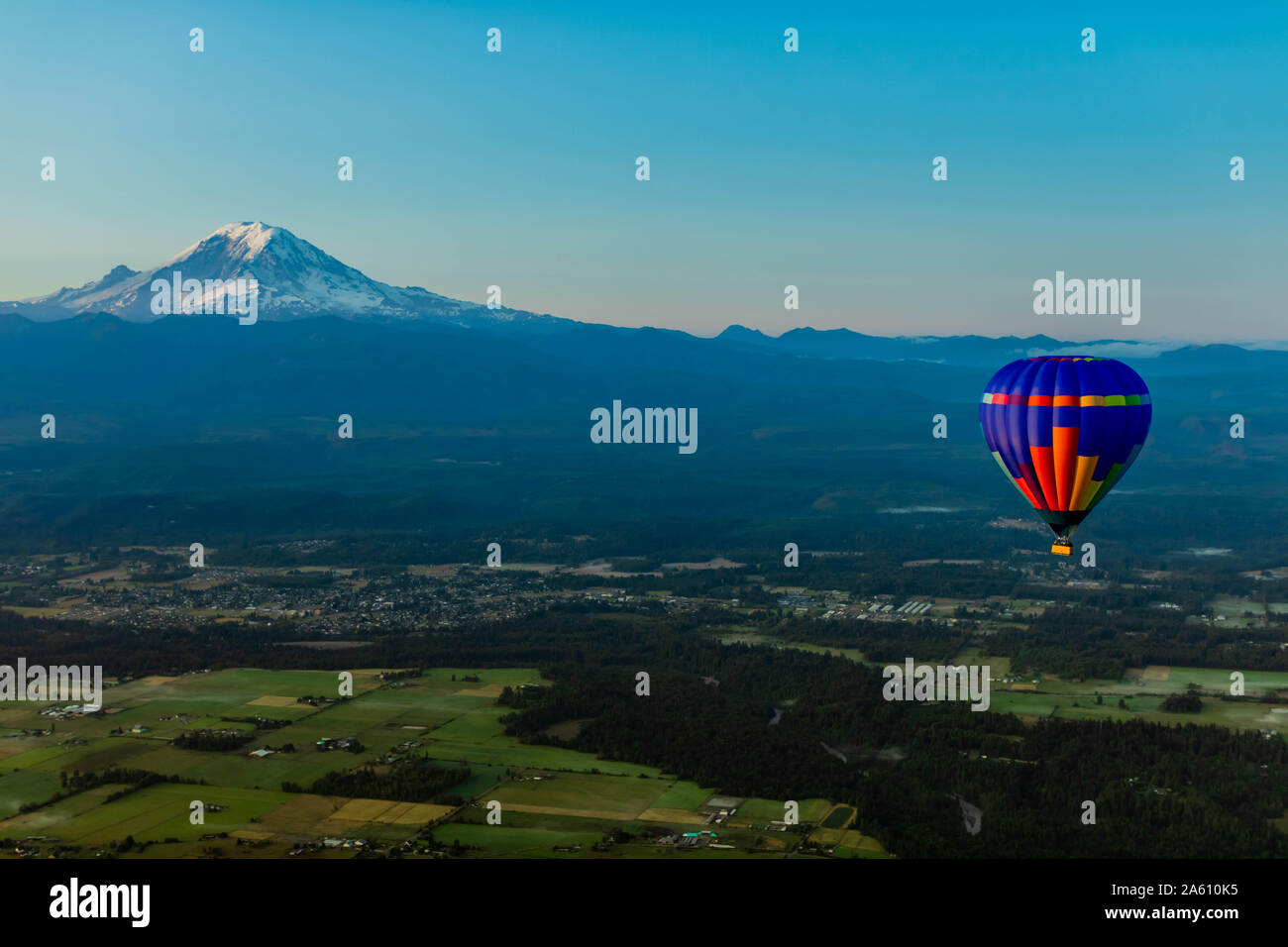 Aerial view of hot air balloon floating over farmland and Mount Rainier in the distance, Washington State, United States of America, North America Stock Photo