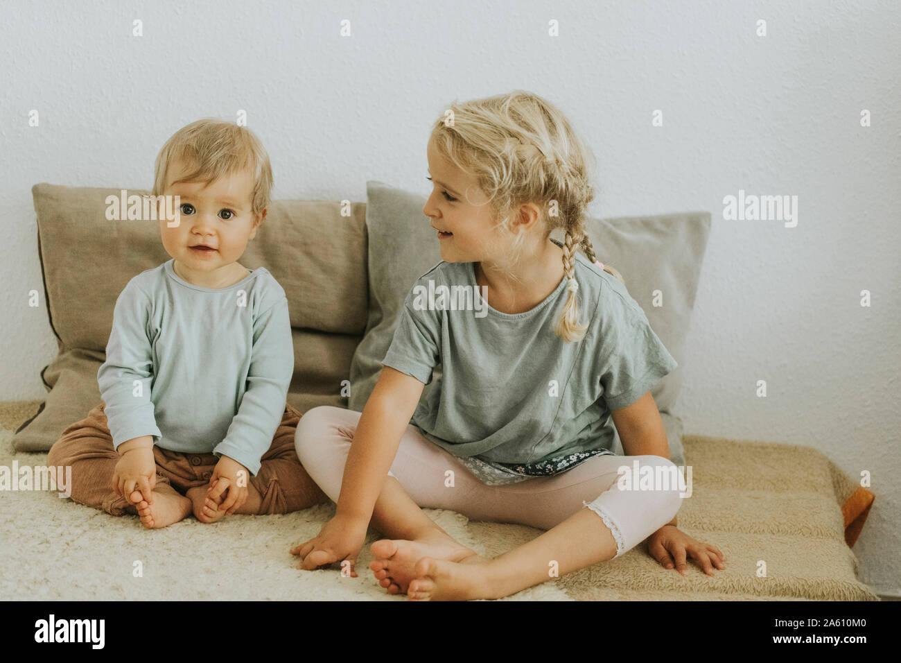 Two sisters sitting side by side at home Stock Photo