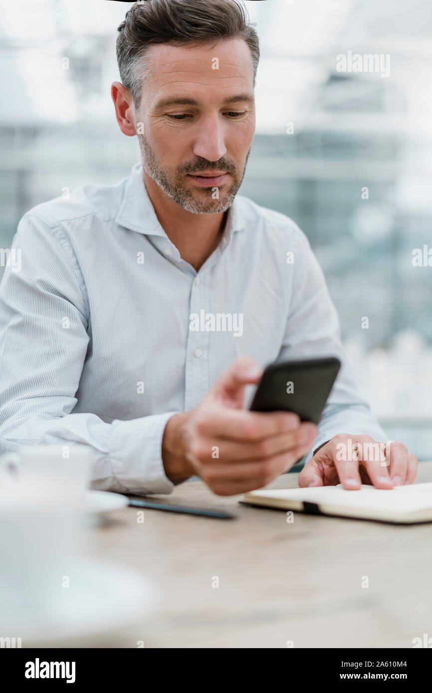 Businessman using cell phone in a cafe Stock Photo