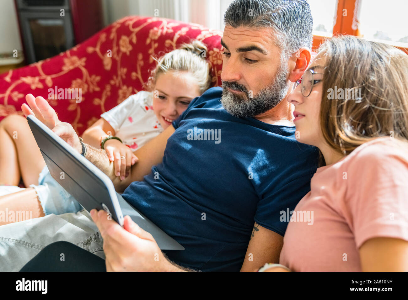 Father with two daughters looking at tablet on couch at home Stock Photo