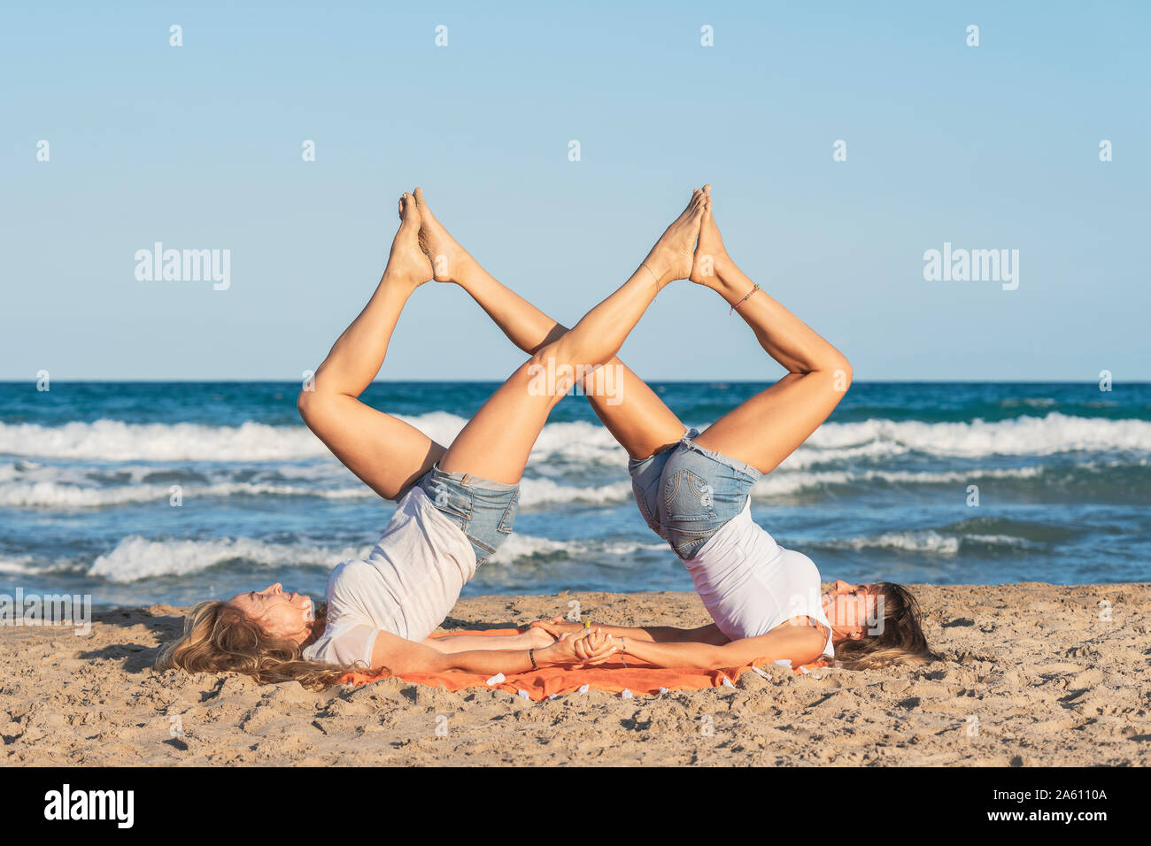 Two women praticing Acro Yoga on the beach Stock Photo