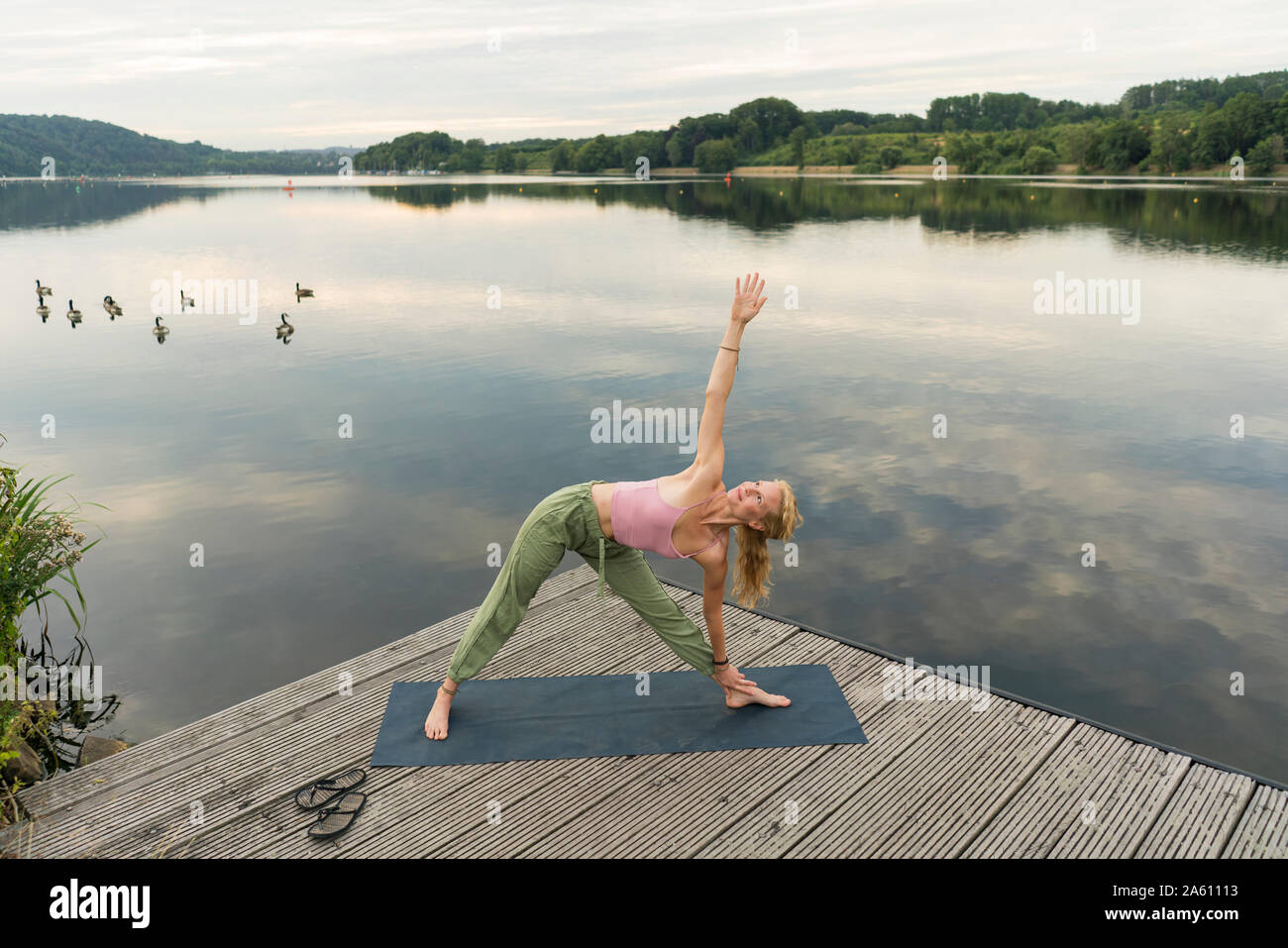 Young woman doing gymnastics on a jetty at a lake Stock Photo