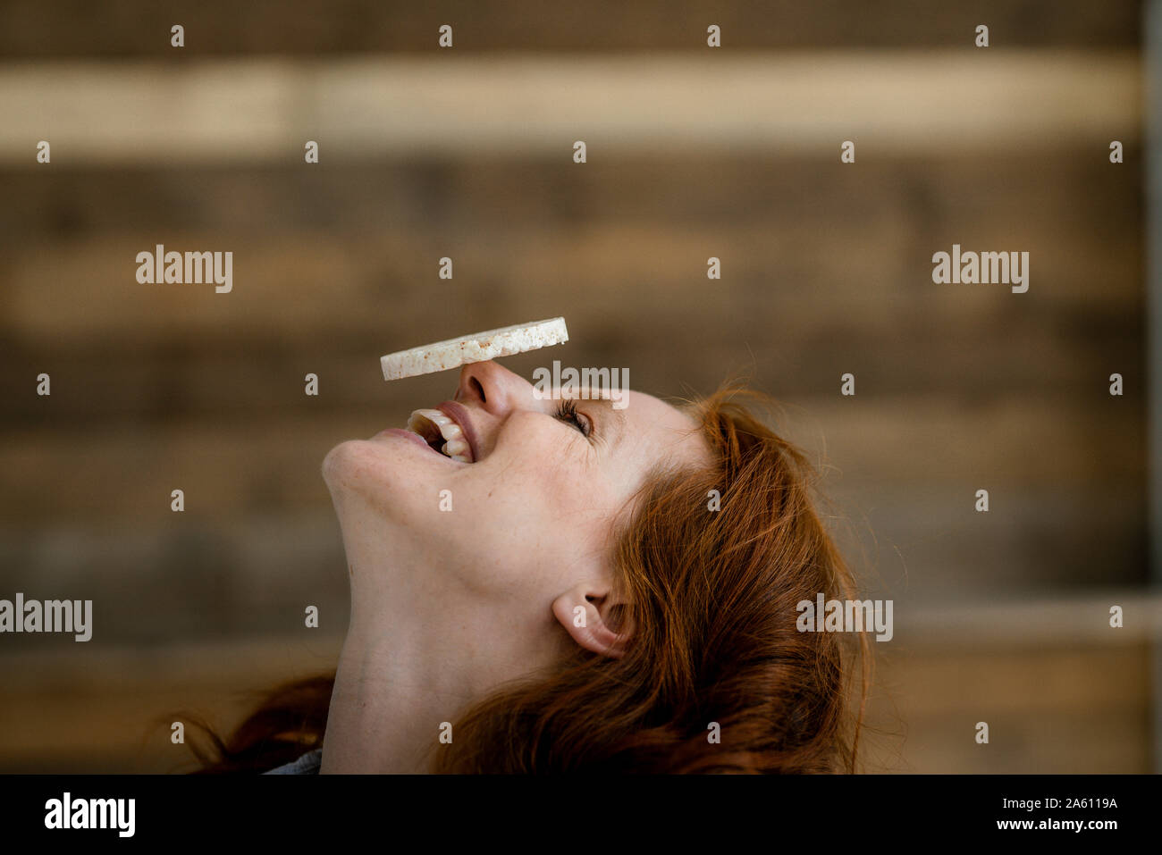 Laughing woman balancing rice cake on her nose Stock Photo