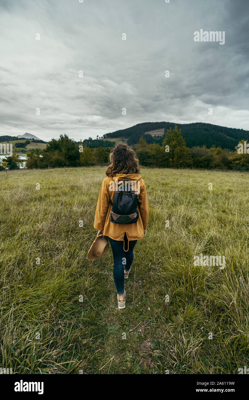 Young woman wearing yellow coat and colored pigtails, riding bike in