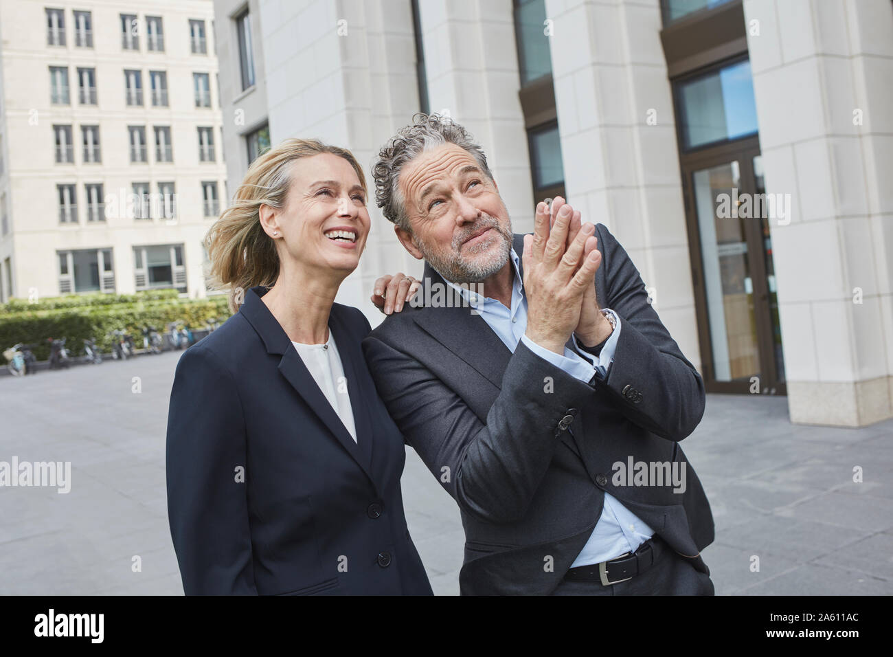 Happy businessman and businesswoman in the city looking up Stock Photo
