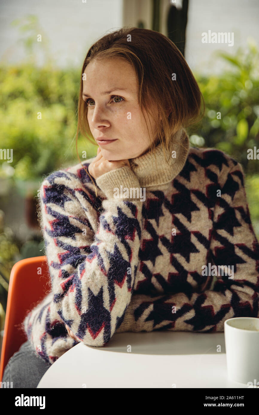 Young woman with glasses wearing fluffy sweater looking sideways Stock Photo