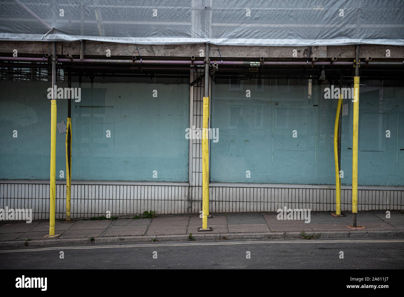 a street scene of an abandoned building in torquay surrounded with scaffolding with yellow sleeves. Stock Photo