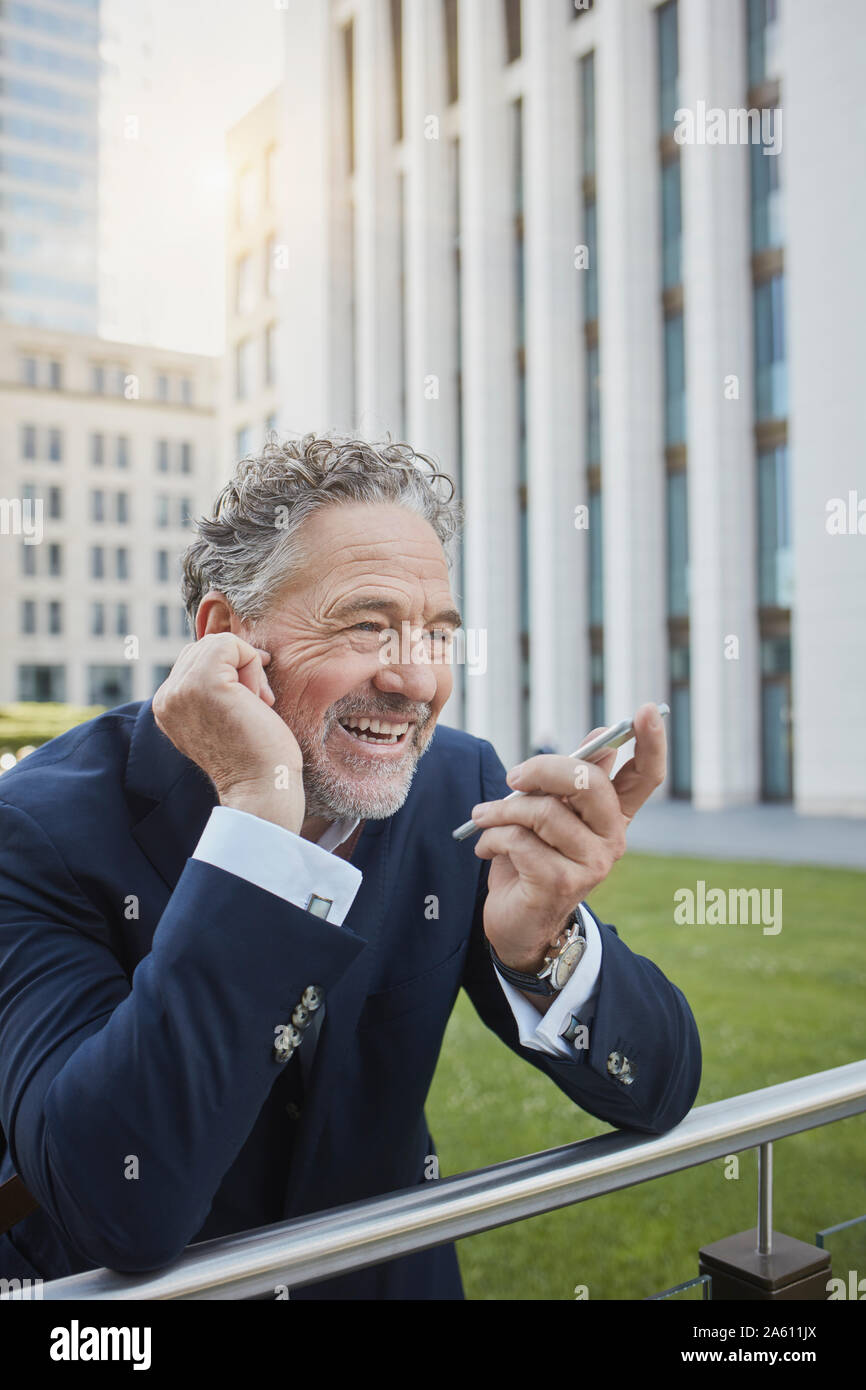Laughing mature businessman using smartphone in the city Stock Photo