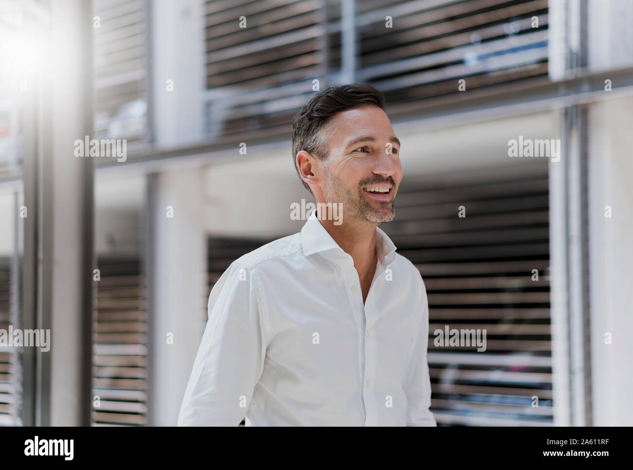 Smiling businessman at a car park wearing white shirt Stock Photo