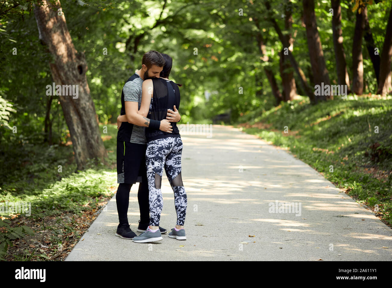 Sporty couple hugging on forest path Stock Photo - Alamy