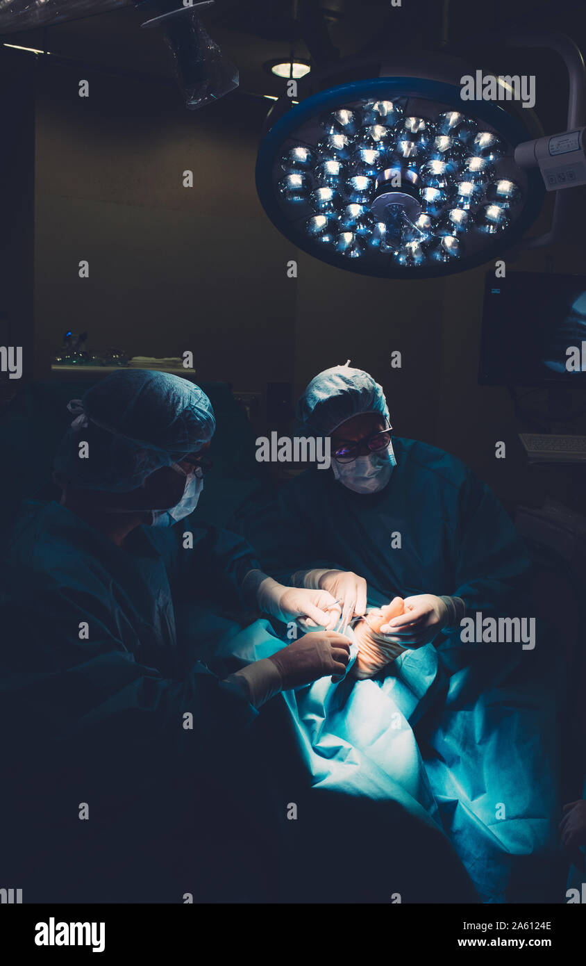 Surgeons during a foot surgery Stock Photo