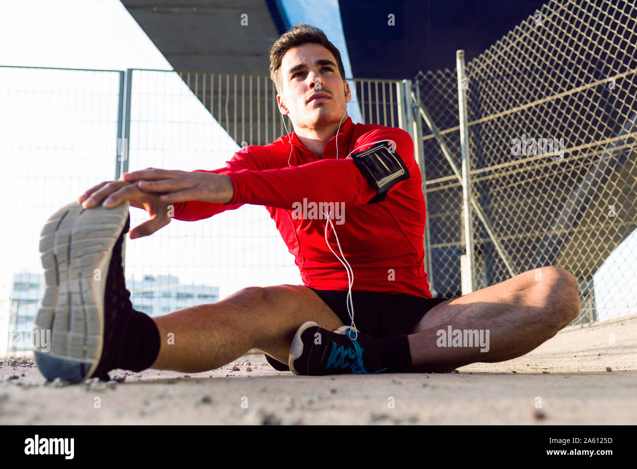 Jogger with smartphone in arm pocket stretching his leg Stock Photo