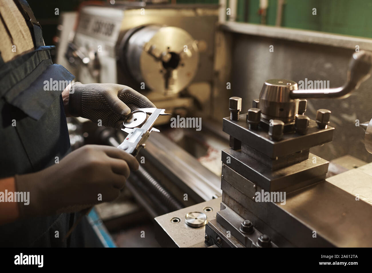 Close-up of manual worker in protective gloves measuring metal detail with special equipment Stock Photo