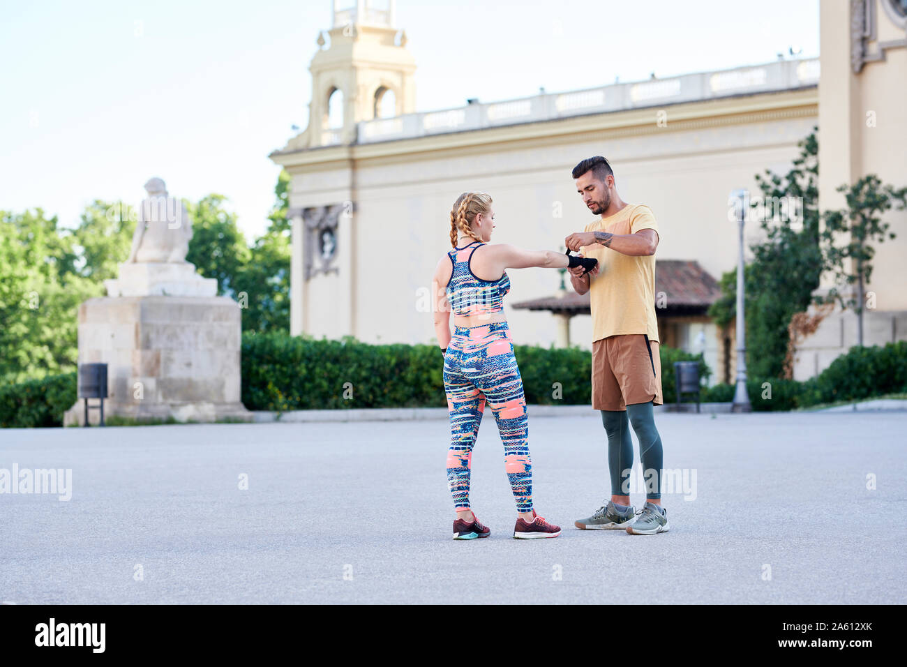 Fitness coach practicing boxing class with young woman outdoors in the city applying bandage Stock Photo
