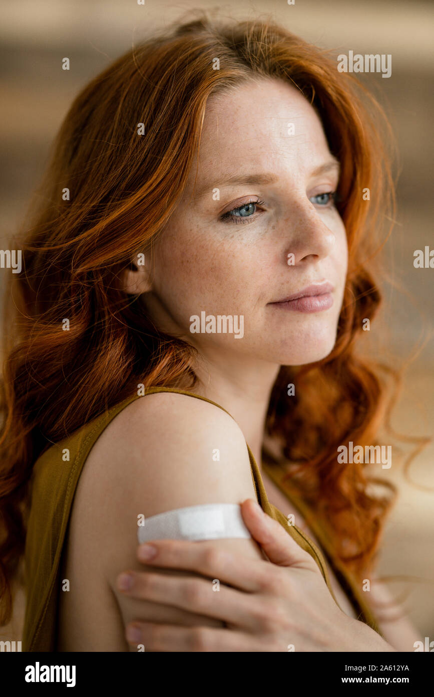 Portrait of redheaded woman with band-aid on her shoulder Stock Photo
