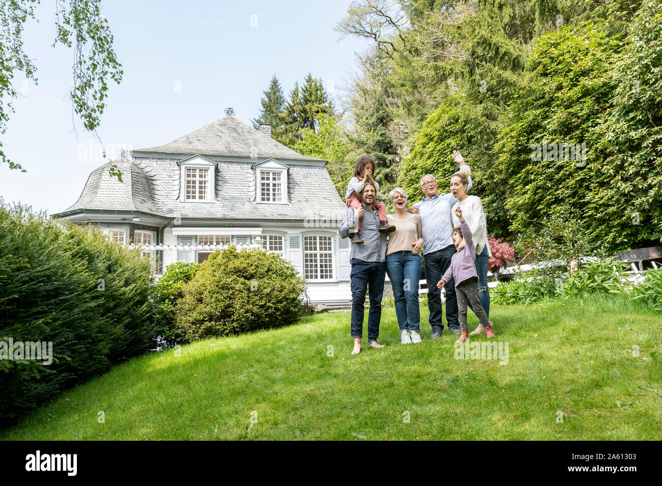 Happy extended family standing in garden of their home Stock Photo