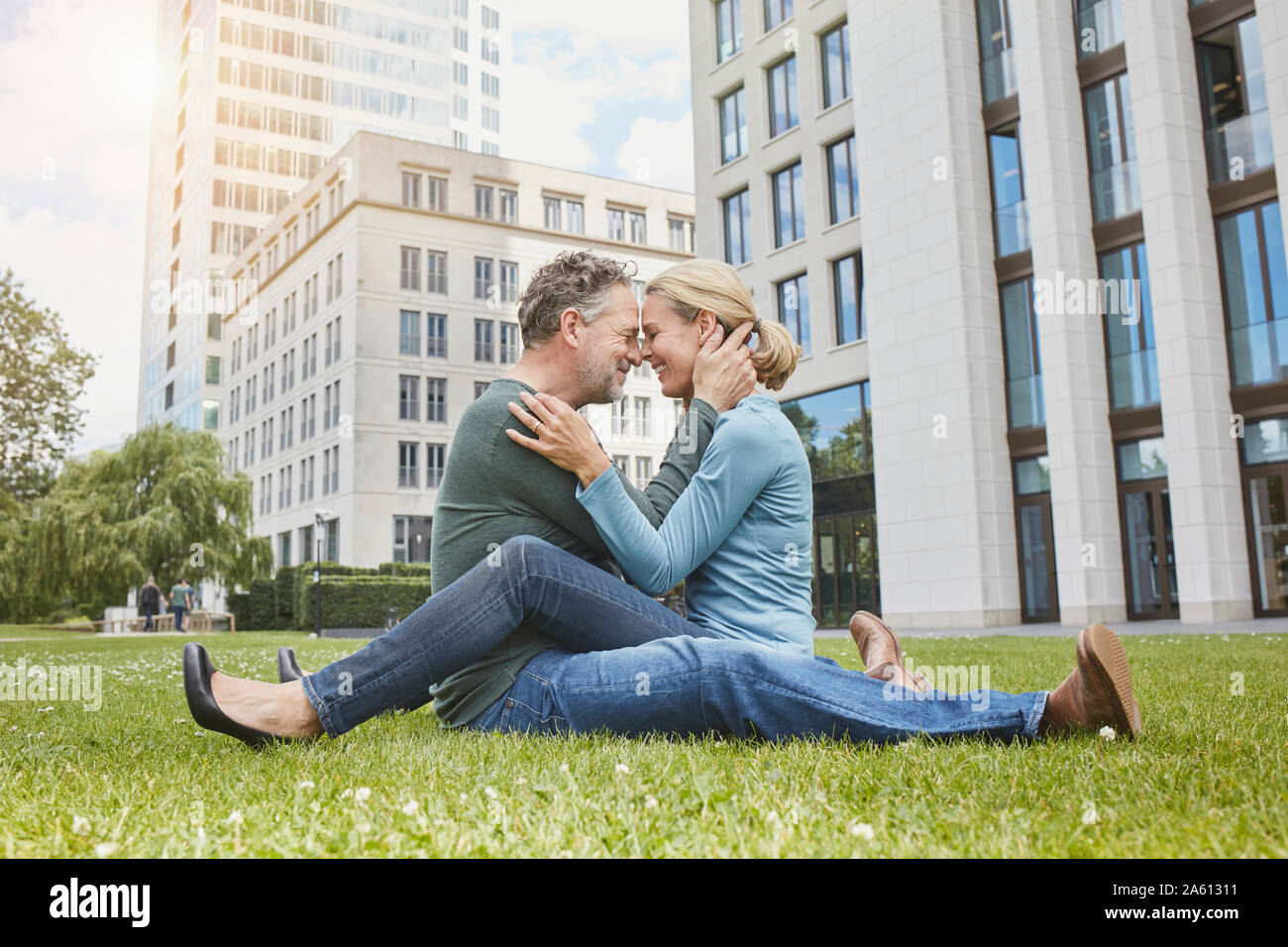 Happy mature couple cuddling on lawn in the city Stock Photo